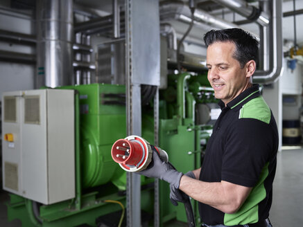 Combined heat and power plant, worker holding high current plug - CVF00438