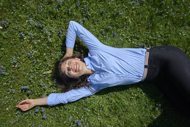Porträt einer glücklichen jungen Frau, die sich auf einer Wiese entspannt - BEF00041