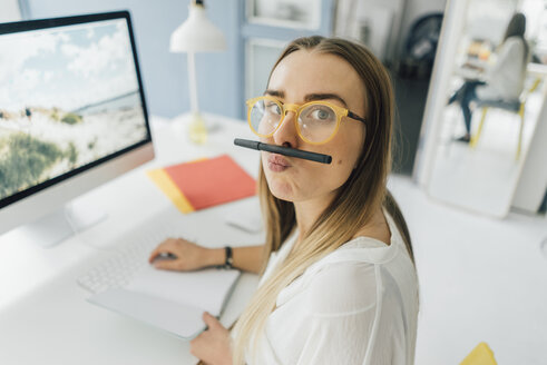 Portrait of funny young woman at desk pouting mouth - GUSF00744