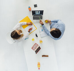 Two business people at meeting table in office, top view - GUSF00754