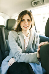 Portrait of young businesswoman sitting on backseat of a car - VABF01572