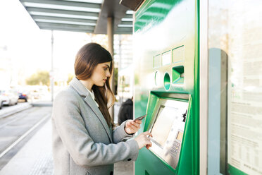 Spanien, Barcelona, Frau kauft Fahrkarte am Automaten im Bahnhof - VABF01587