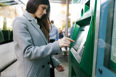 Spanien, Barcelona, Frau kauft Fahrkarte am Automaten im Bahnhof, lizenzfreies Stockfoto