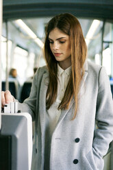 Porträt einer jungen Frau beim Entwerten einer Fahrkarte in der Straßenbahn - VABF01592