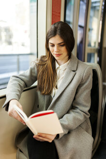 Porträt einer jungen Frau, die in der Straßenbahn ein Buch liest - VABF01595