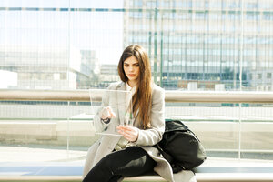 Spain, Barcelona, portrait of young businesswoman using futuristic portable device at station - VABF01597