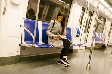 Spain, Barcelona, woman sitting in underground train using cell phone - VABF01599
