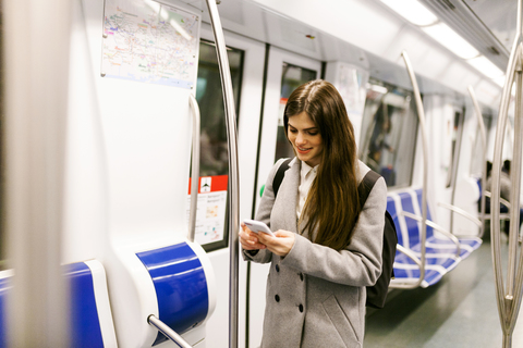 Spain, Barcelona, young woman in underground train looking at cell phone stock photo