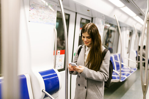 Spanien, Barcelona, junge Frau in der U-Bahn schaut auf ihr Handy - VABF01602