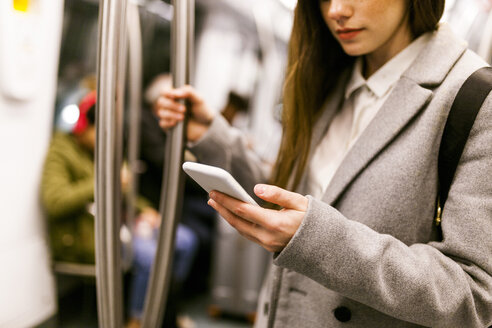 Geschäftsfrau benutzt Handy in U-Bahn, Teilansicht - VABF01603