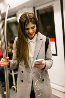 Junge Geschäftsfrau benutzt Mobiltelefon in der U-Bahn - VABF01605
