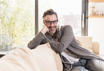 Portrait of smiling man relaxing on couch at home - UUF13503