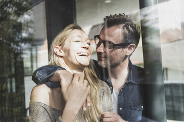 Happy mature couple behind windowpane at home - UUF13508