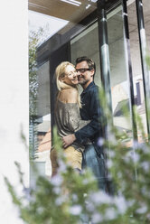 Glückliches reifes Paar steht auf der Terrasse seines Hauses - UUF13511