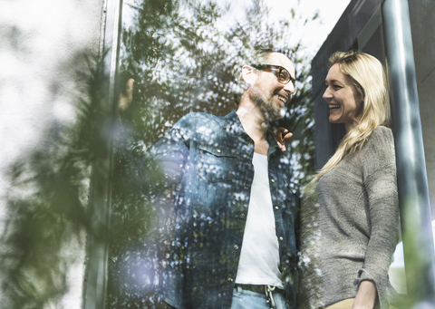 Lachendes reifes Paar, das auf der Terrasse seines Hauses steht, lizenzfreies Stockfoto
