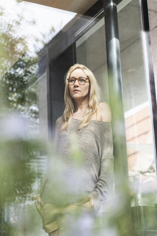 Porträt einer blonden reifen Frau, die auf einer Terrasse steht, lizenzfreies Stockfoto