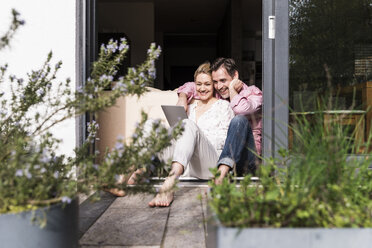 Mature couple relaxing together at open terrace door using tablet - UUF13547