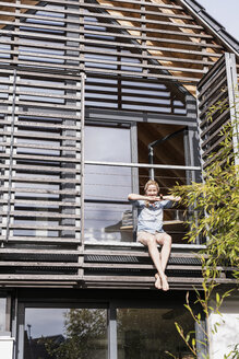 Frau entspannt sich auf dem Balkon ihres Hauses - UUF13552