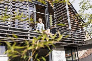 Woman relaxing on balcony of her house - UUF13553