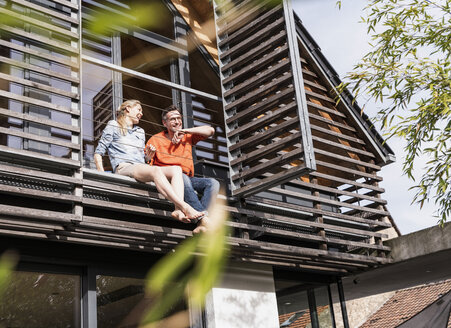 Reifes Paar entspannt zusammen auf dem Balkon ihres Hauses - UUF13554