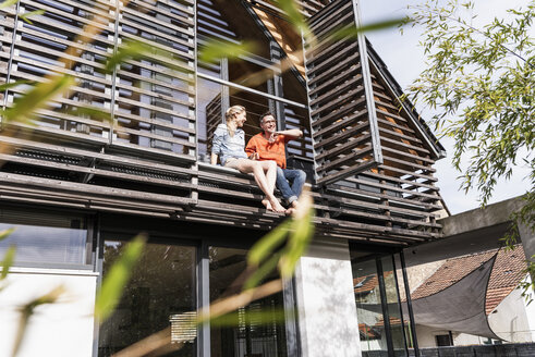 Reifes Paar entspannt zusammen auf dem Balkon ihres Hauses - UUF13555