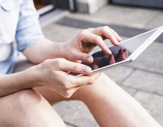 Woman sitting on terrace using tablet, close-up - UUF13574