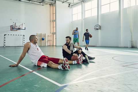 Basketballspieler in der Pause, auf dem Spielfeld sitzend, lizenzfreies Stockfoto