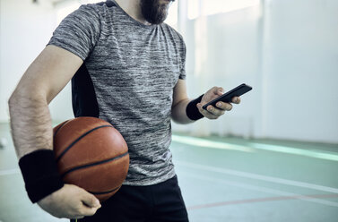 Mann mit Basketball und Smartphone, innen - ZEDF01377