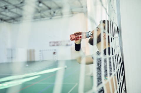 Basketballspieler trinkt aus einer Plastikflasche, lizenzfreies Stockfoto