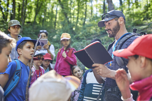 Mann liest Kindern bei einem Ausflug in den Wald vor - ZEDF01393