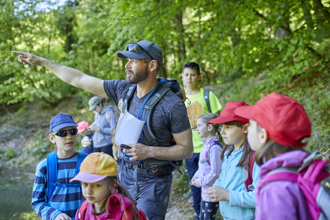 Mann spricht mit Kindern bei einem Ausflug in den Wald, lizenzfreies Stockfoto