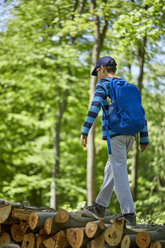Junge mit Rucksack balanciert auf Baumstämmen im Wald - ZEDF01403