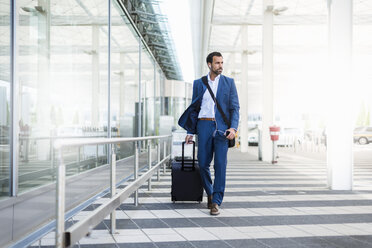 Businessman with trolley and smartphone at airport - DIGF04188