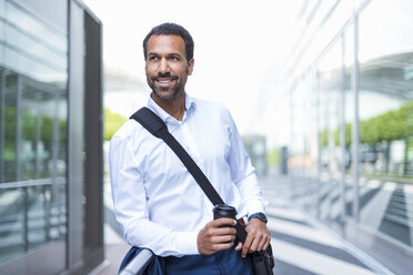 Geschäftsmann mit Kaffee zum Mitnehmen und Laptoptasche am Flughafen - DIGF04200