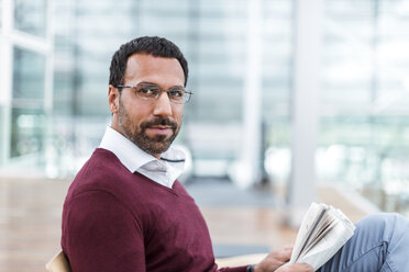 Geschäftsmann liest eine Zeitung in einer Wartehalle - DIGF04220