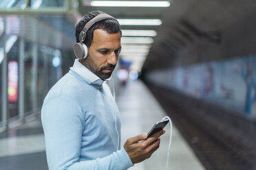 Businessman using smartphone at metro station - DIGF04234