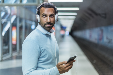 Geschäftsmann benutzt Smartphone in der U-Bahn-Station, lizenzfreies Stockfoto