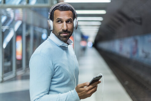 Geschäftsmann benutzt Smartphone in der U-Bahn-Station - DIGF04235