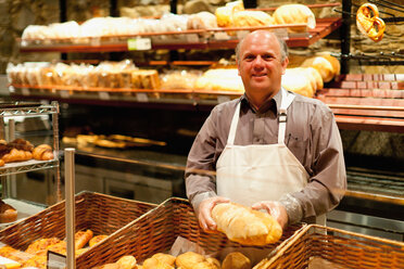 Lächelnder Bäcker mit einem Laib Brot - CUF01179