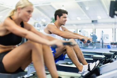 Couple using rowing machines in gym - CUF01187