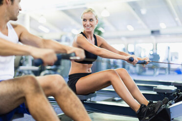 Couple using rowing machines in gym - CUF01188