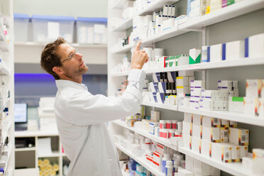 Pharmacist browsing medicines on shelf - CUF01197