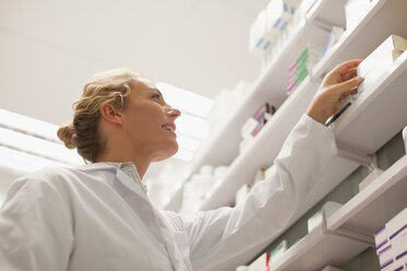 Pharmacist browsing medicines on shelf - CUF01198