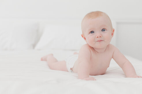 Lächelndes Baby auf dem Bett liegend - CUF01205