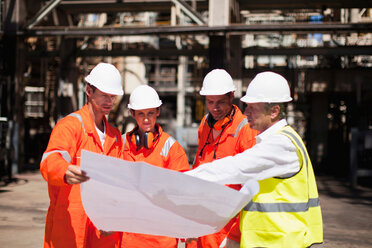 Workers with blueprints at oil refinery - CUF01210
