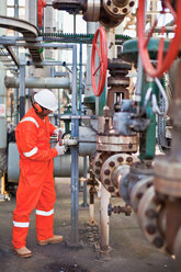 Arbeiter beim Einstellen von Messgeräten in einer Ölraffinerie - CUF01214