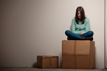 Teenage girl sitting on cardboard box - CUF01237