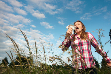 Woman sneezing in tall grass - CUF01240