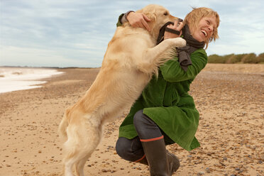 Frau trainiert, spielt mit Hund, Strand - CUF01314