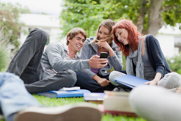 Students using cell phone on grass - CUF01366
